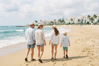 Famille de quatre marchant sur la plage en Espagne